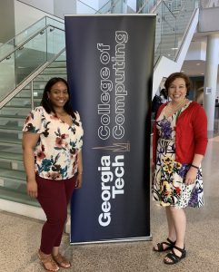 Alyshia Jackson and Amanda Girard stand by the Georgia Tech College of Computing banner at the Spring 2019 Expo